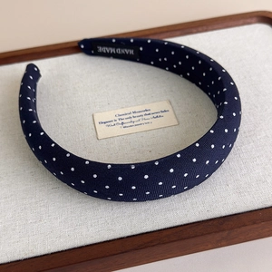 Dettaglio del cerchietto blu navy a pois fatto a mano con etichetta del marchio