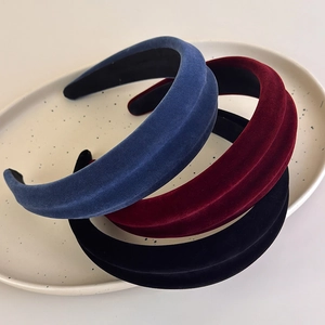 Close-up of velvet padded headbands in navy, burgundy, and black on a ceramic plate
