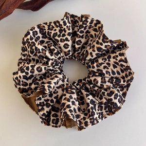 Close-up of leopard print hair scrunchie made of textured woven fabric for ponytails