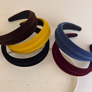 Detail view of five velvet padded headbands in various colors on a white ceramic plate