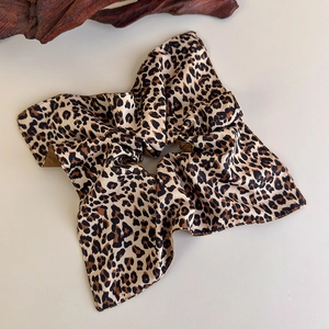 Close-up of leopard print satin scrunchie with silky texture on a beige background