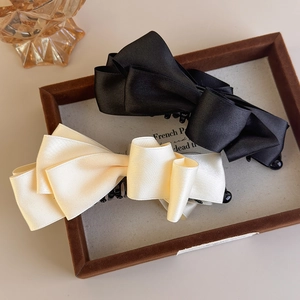 Detailed view of large black and beige satin bow banana clips for high ponytail hairstyles