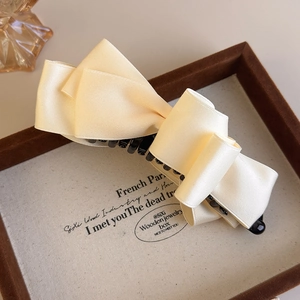 Macro shot of elegant cream satin ribbon texture on the multi-layered bow banana hair clip