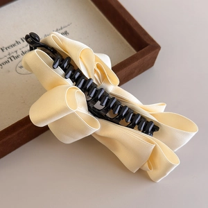 Detail view of large cream satin bow banana hair clip with elegant multi-layer ribbon pleats