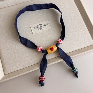 Detail of blue fabric scarf necklace with red heart wood bead and colorful charms