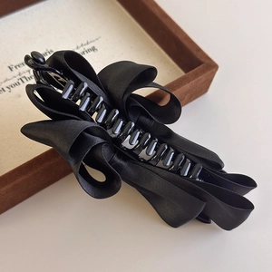 Detailed view of elegant black satin bow banana clip with secure multi-tooth grip