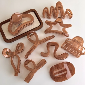 Assorted amber translucent hair claws in various geometric and bow shapes on white background