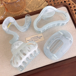 Detail view of four blue marble hair claw clips displayed on a vintage tray