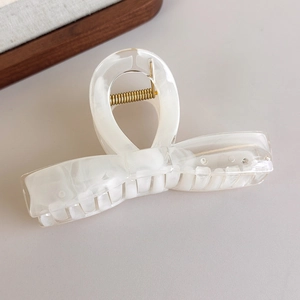 Détail d'une grande pince à cheveux blanc crème avec finition marbrée et ressort en métal