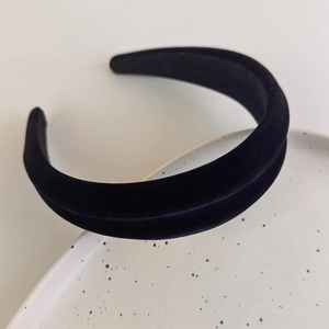 Detailed macro view of high-crown black velvet headband on a textured ceramic dish