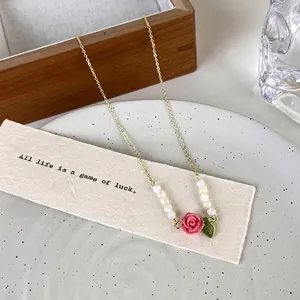 Elegant French style rose and pearl beaded gold necklace on decorative white plate