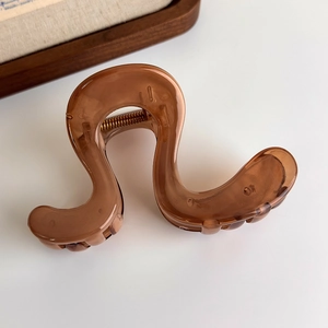 Close-up of translucent amber brown wave hair claw clip with glossy resin finish