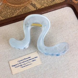 Detailed view of a light blue translucent wavy hair claw clip with a gold metal spring