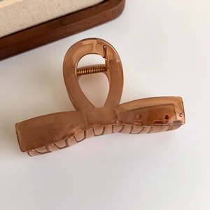 Top view of a translucent amber jelly butterfly hair claw clip with a metal spring