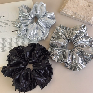 Vue détaillée de grands chouchous pour cheveux en argent métallisé et noir brillant