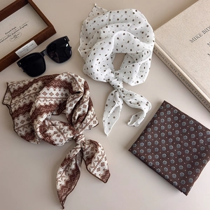 Close-up of brown polka dot and floral silk scarves in a stylish flat lay arrangement