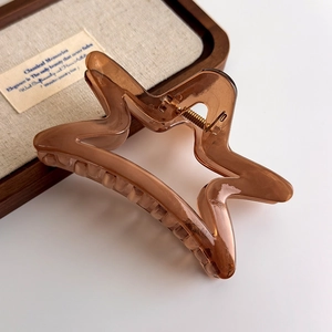 Macro detail of star-shaped amber hair claw clip with a glossy finish and gold spring