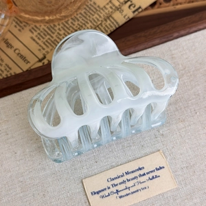 Detailed macro view of white marble acetate hair claw clip on vintage background