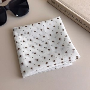 Detailed macro view of white chiffon square scarf with brown polka dots and rolled edges