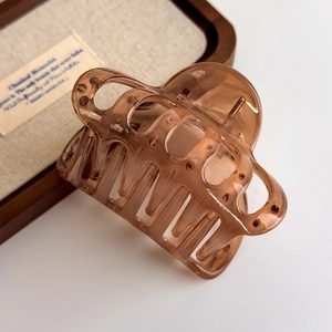 Detail of amber translucent hair claw clip with smooth resin finish on wooden display