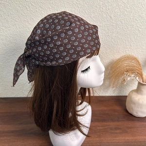 Detail view of brown floral headscarf tied on a hair model with white dot print patterns
