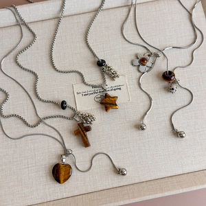 Macro view of flower and heart pendants made of tiger eye stone on silver chains