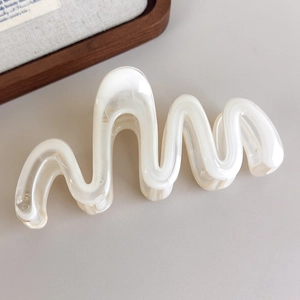 Détail de la pince à cheveux ondulée crème avec texture nacrée et finition en acétate