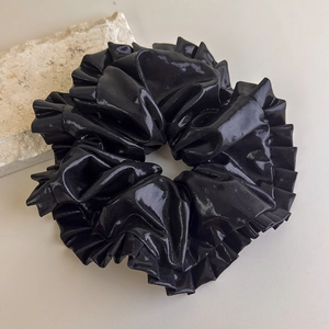 Détail d'un grand chouchou noir avec éclat métallique laser et texture à bords froncés