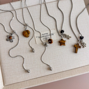 Flat lay of tiger eye necklaces featuring heart and flower pendants on beige fabric