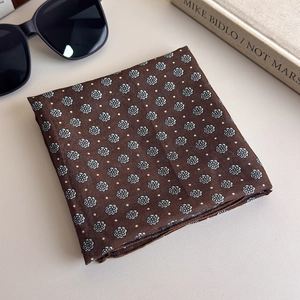 Folded brown polka dot floral scarf with daisy patterns next to sunglasses and a book