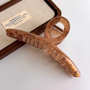 Detailed macro view of amber translucent hair claw clip with modern twisted design