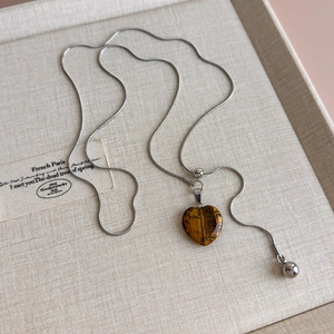 Detailed macro view of heart-shaped tiger eye stone pendant on adjustable snake chain