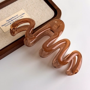 Close-up of translucent amber brown wave hair claw clip with glossy resin finish