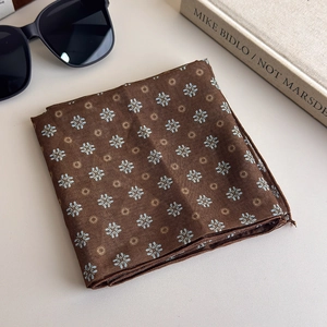 Detail of dark brown polka dot floral silk scarf with sunglasses and art book