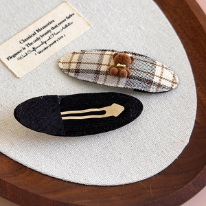 Detail of plaid fabric hair clips featuring cute flocked bears and golden metal duckbill clips