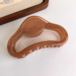 Close-up of translucent amber resin hair claw clip showing fine teeth and smooth finish