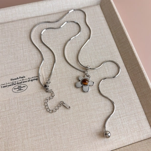 Macro detail of silver flower pendant with tiger eye stone on adjustable snake chain