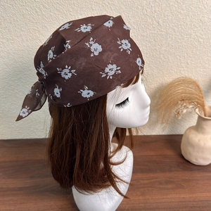 Close-up of brown floral silk scarf tied on a model with vintage aesthetic detail