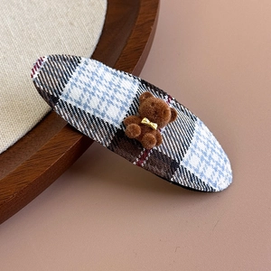 Close-up of a blue and brown plaid fabric hair clip featuring a cute flocked 3D bear detail