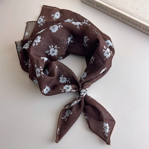 Detail of a tied dark brown floral silk scarf with retro polka dot and flower pattern