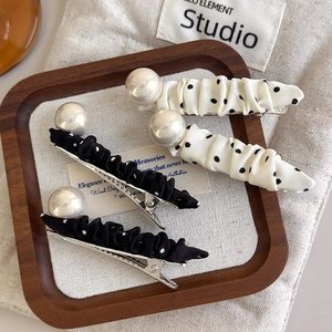 Elegant polka dot and pearl hair clips set displayed on a wooden tray with soft lighting