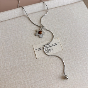 Detailed macro of a silver snake chain necklace with an amber tiger eye flower pendant