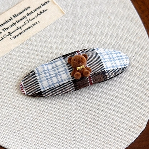 Detailed close-up of a blue plaid BB hair clip with a cute brown flocked bear ornament
