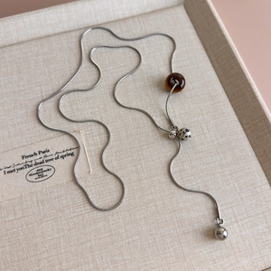 Detail of silver snake chain necklace featuring tiger eye and spotted stone beads