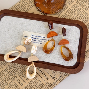Vintage tortoiseshell resin geometric drop earrings in amber and cream on a wooden tray