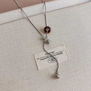 Detail of vintage Y-shaped necklace with tiger eye stone and resin ring on fabric