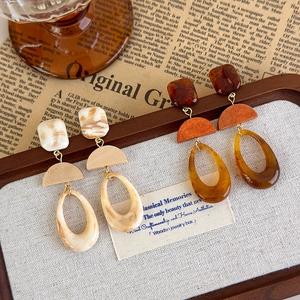 Detail view of retro geometric resin drop earrings in amber and marble patterns