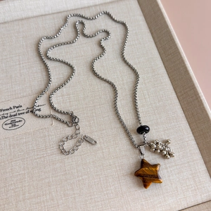 Macro view of star-shaped tiger eye pendant on a silver box chain sweater necklace