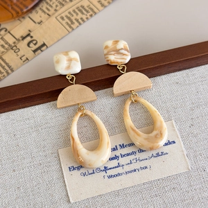 Close-up of retro oval resin drop earrings with marble texture and wood accents