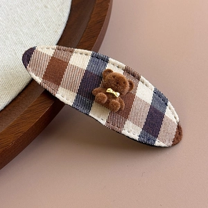 Detailed macro view of the fabric plaid hair clip with a cute flocked brown bear